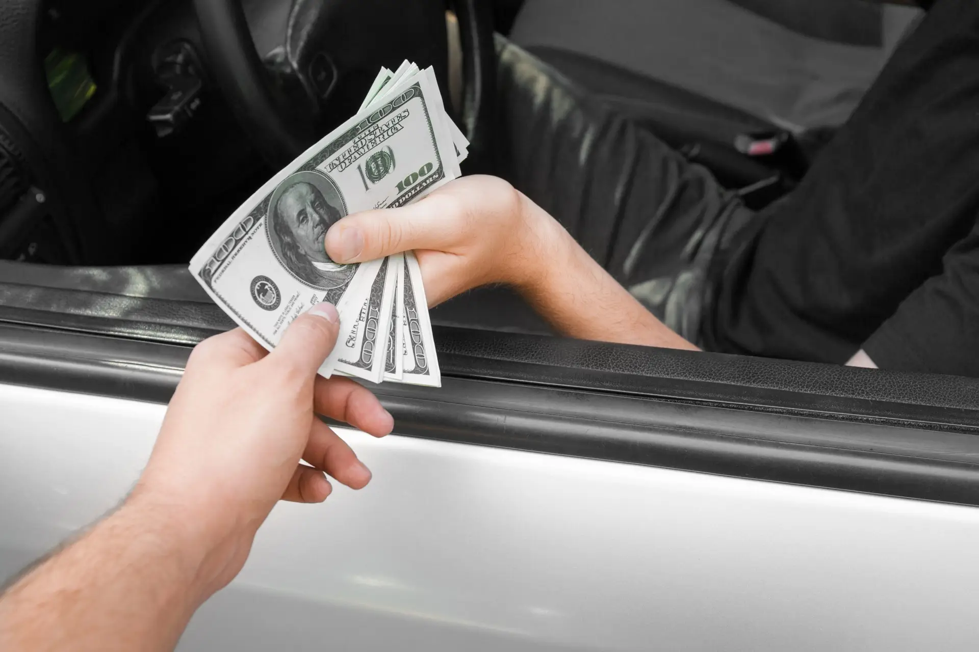 Person handing over cash to first junk car seller, showing common mistake when selling junk car for cash.