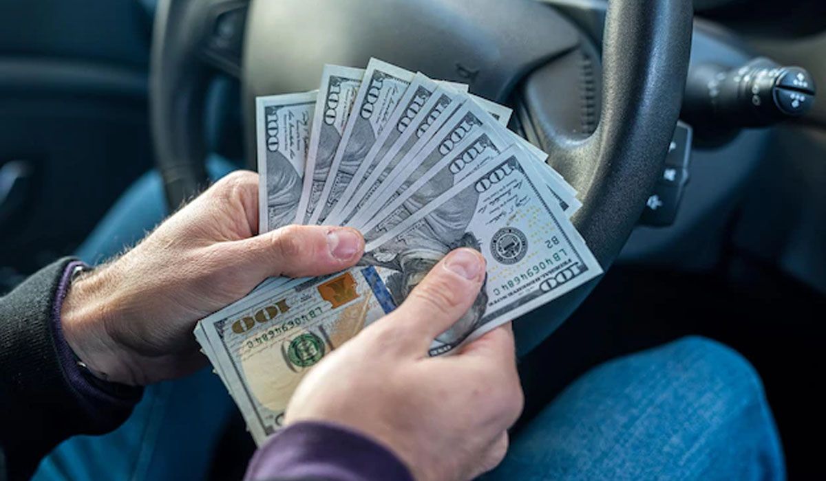 man in a car holding dollar bills
