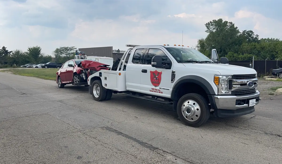 a white truck towing a broken-down red car