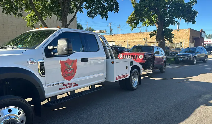 Professional car removal service using a tow truck to transport a damaged vehicle from the roadside safely.