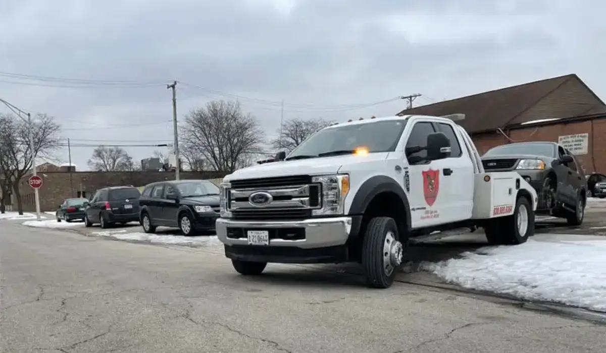 Ford tow truck from A+ Junk N Tow securing a junk car for cash on a snowy day