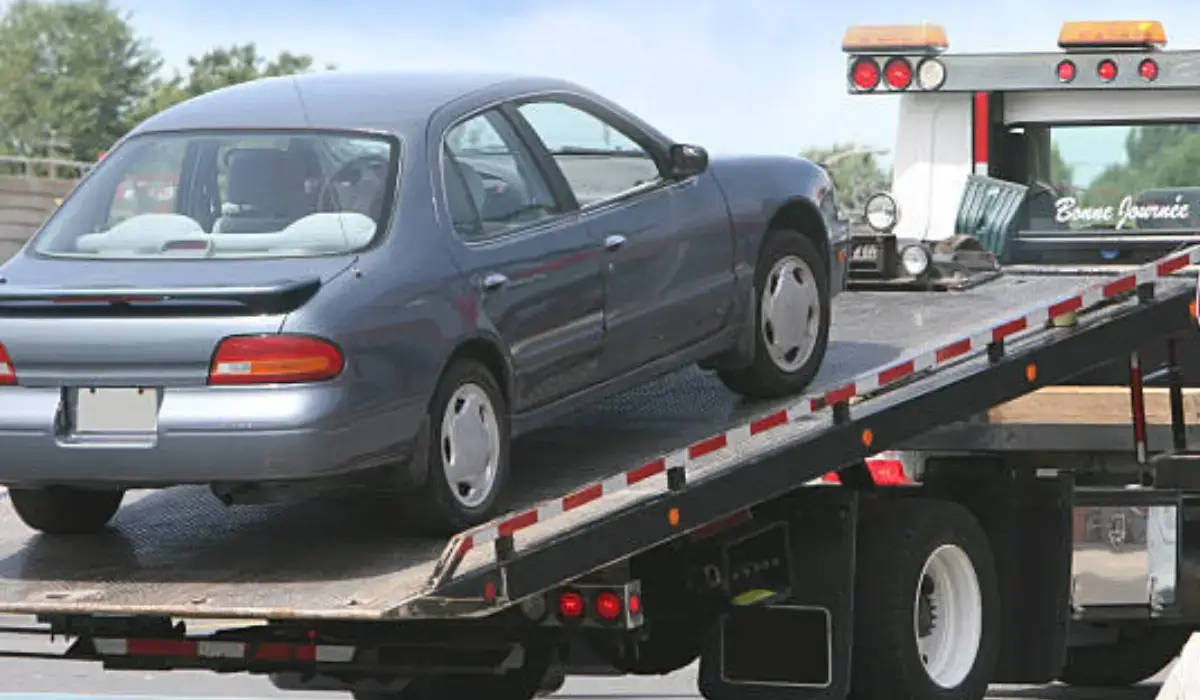 A repossessed car being towed on a flatbed truck, highlighting its transportation process.