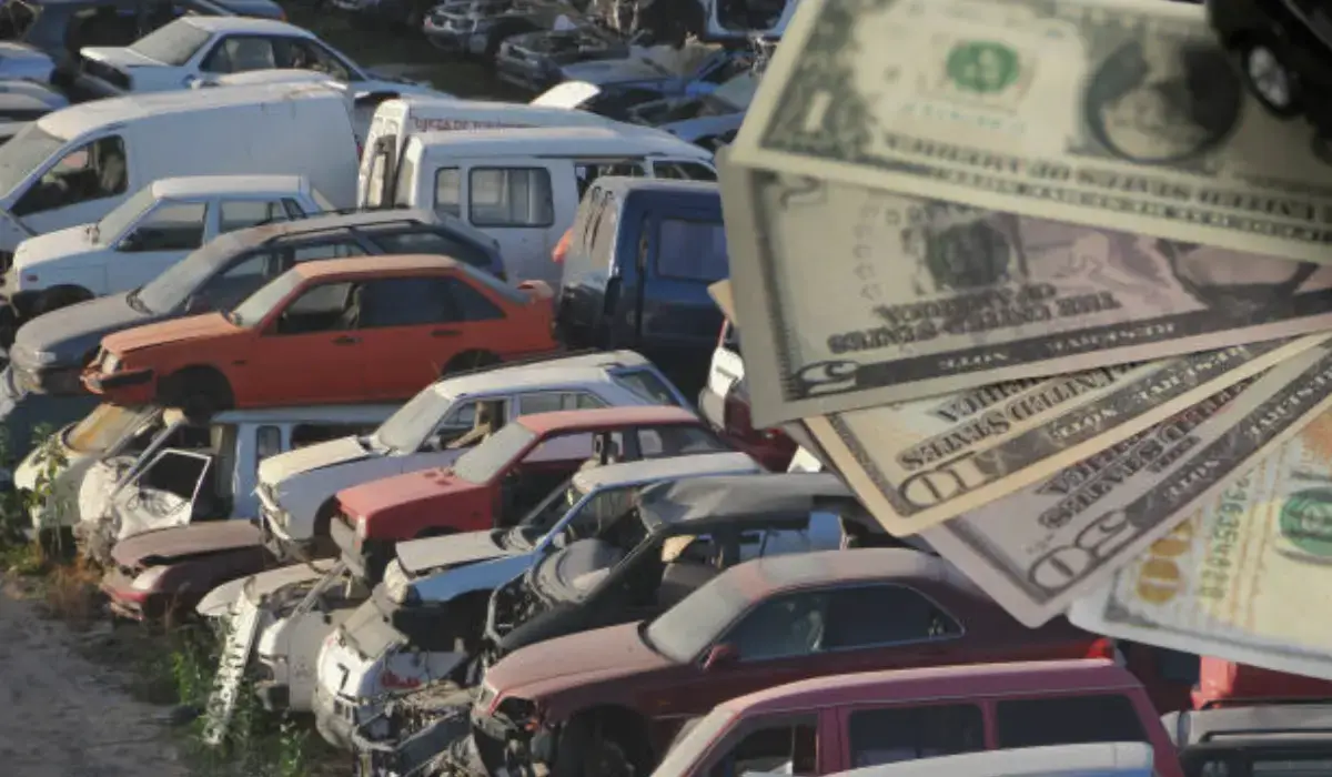 A pile of damaged and old vehicles in a salvage yard with cash in the foreground, symbolizing junk car for cash deals.