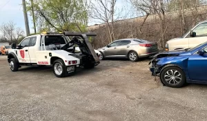 Tow truck preparing to legally remove an abandoned car from a gravel lot in Illinois during daylight.