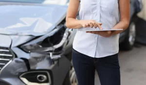 Woman using tablet to assess vehicle damage and answer the question: is my car junk or repairable.