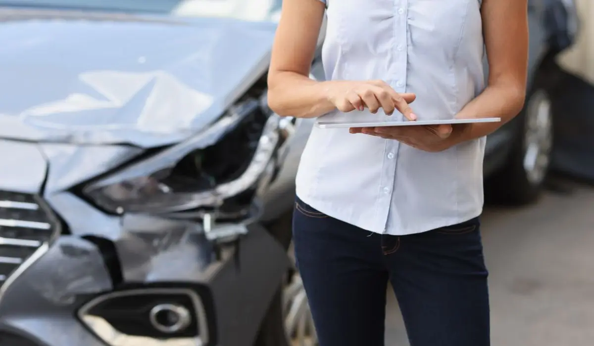 Woman using tablet to assess vehicle damage and answer the question: is my car junk or repairable.
