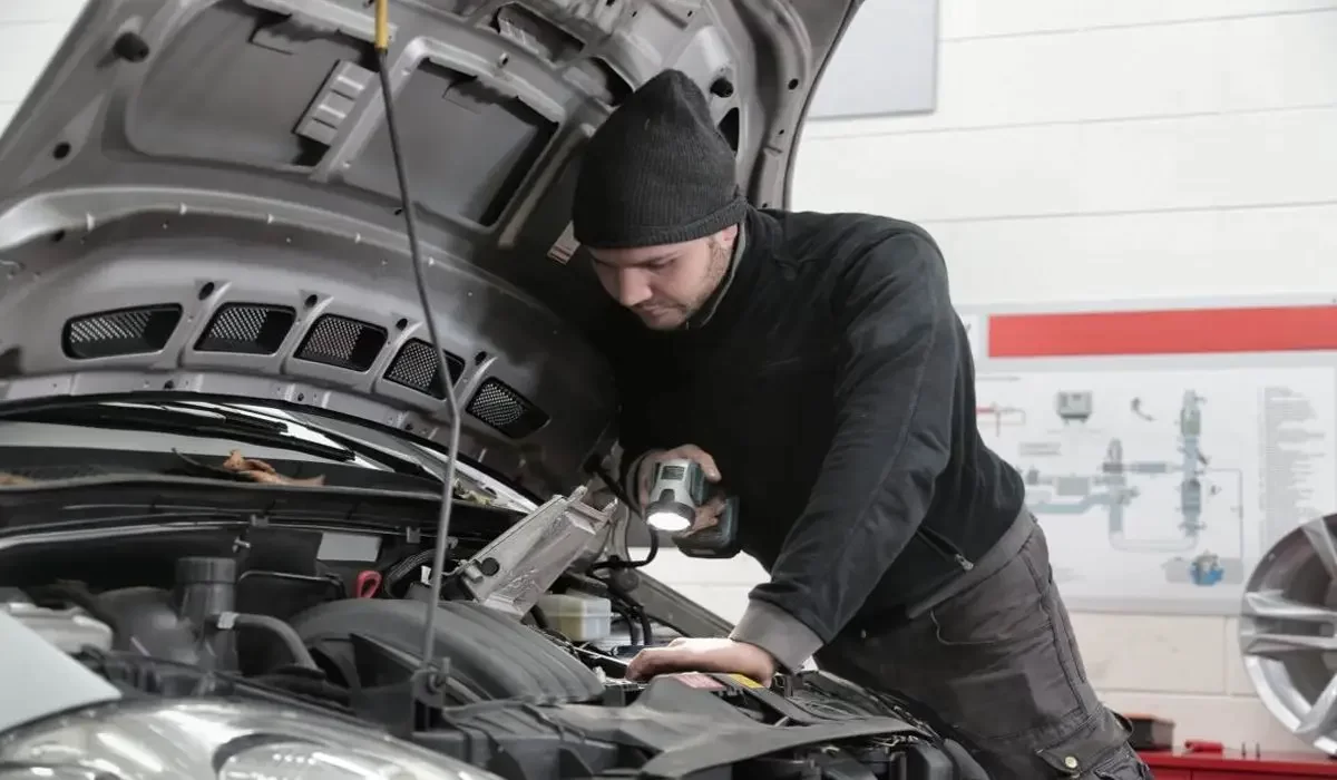 Mechanic inspecting engine with flashlight, helping driver decide answer to question: Is My Car Junk or repairable.